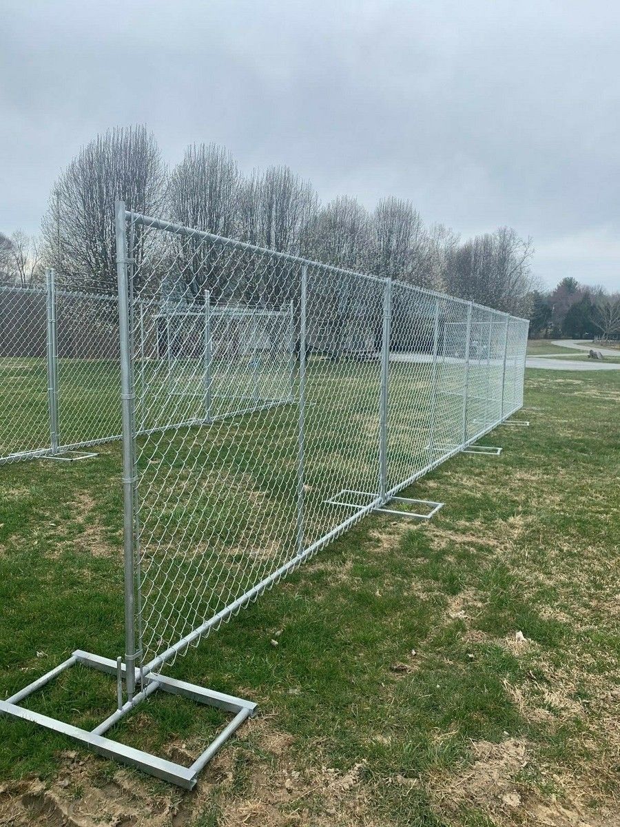 Chain-link fence on a grassy field under a cloudy sky.