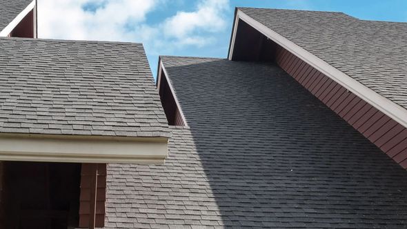 Grey shingle roofs with red trim against a blue sky.