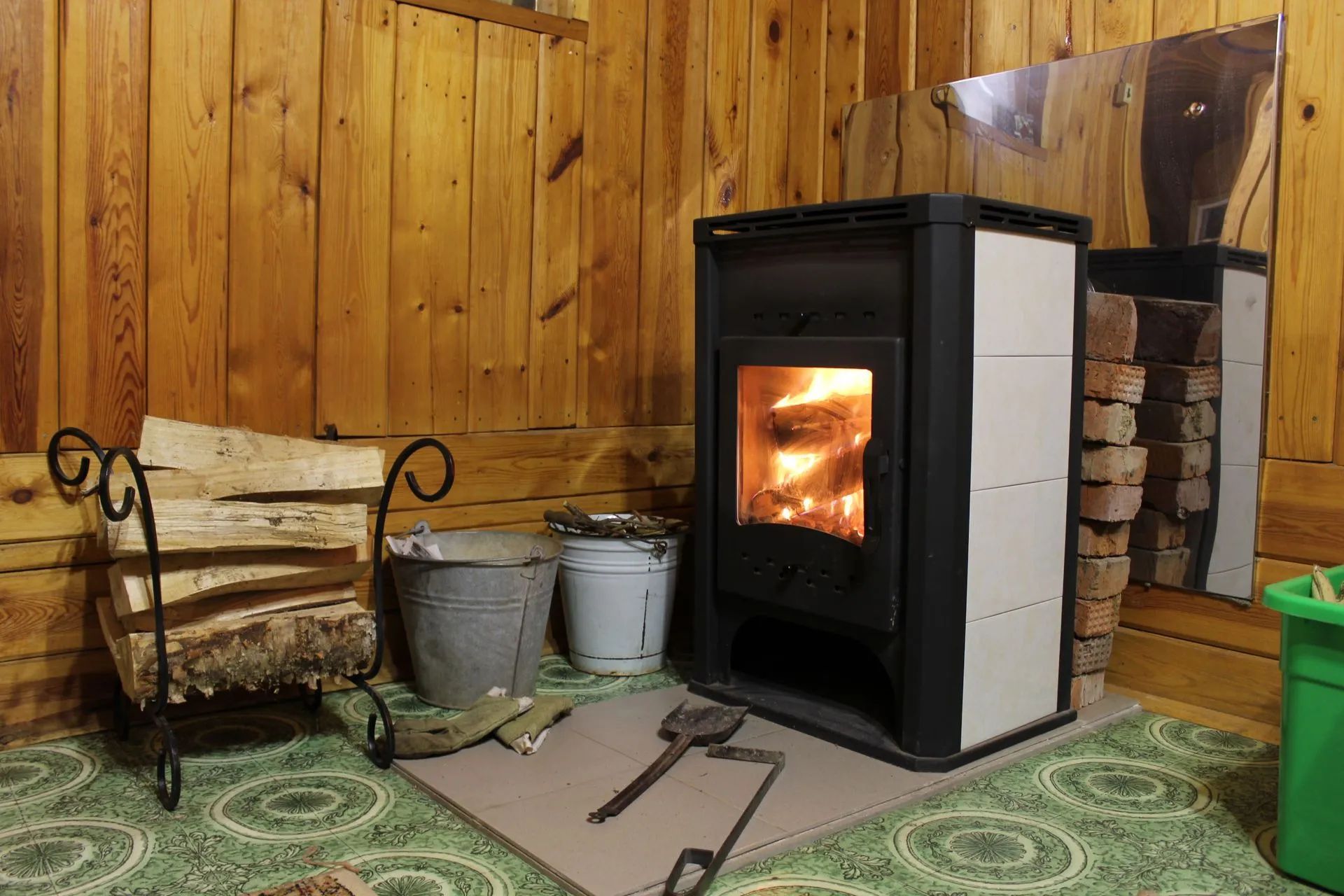 A wood stove is sitting in a room next to a wooden wall.