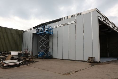Industrial building with a blue scissor lift beside a large open bay door