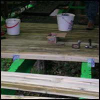 Wooden porch under construction with paint buckets and tools on the floorboards