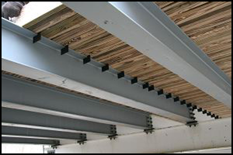 Close-up of metal beams with dark fasteners supporting a wooden slatted ceiling