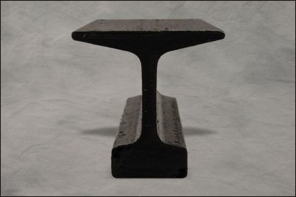 Black metal I-beam section standing upright against a gray background