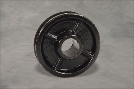 Black metal wheel hub with a central hole on a gray background