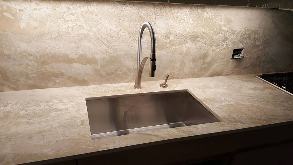 A kitchen sink with a stainless steel faucet on a marble countertop