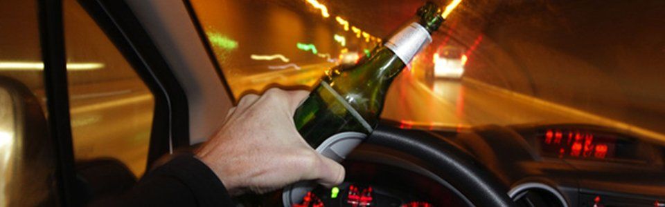 Man driving while holding a bottle of beer