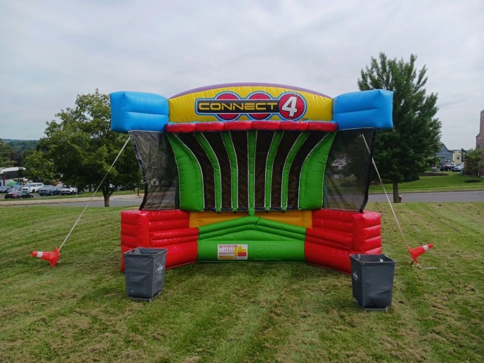 A colorful inflatable game called connect 4 is sitting in a grassy field.