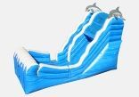 A blue inflatable water slide with dolphins on it.