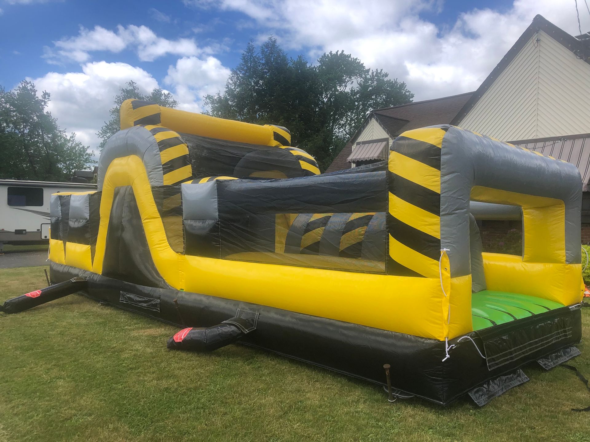 A large inflatable obstacle course is sitting in the grass in front of a house.