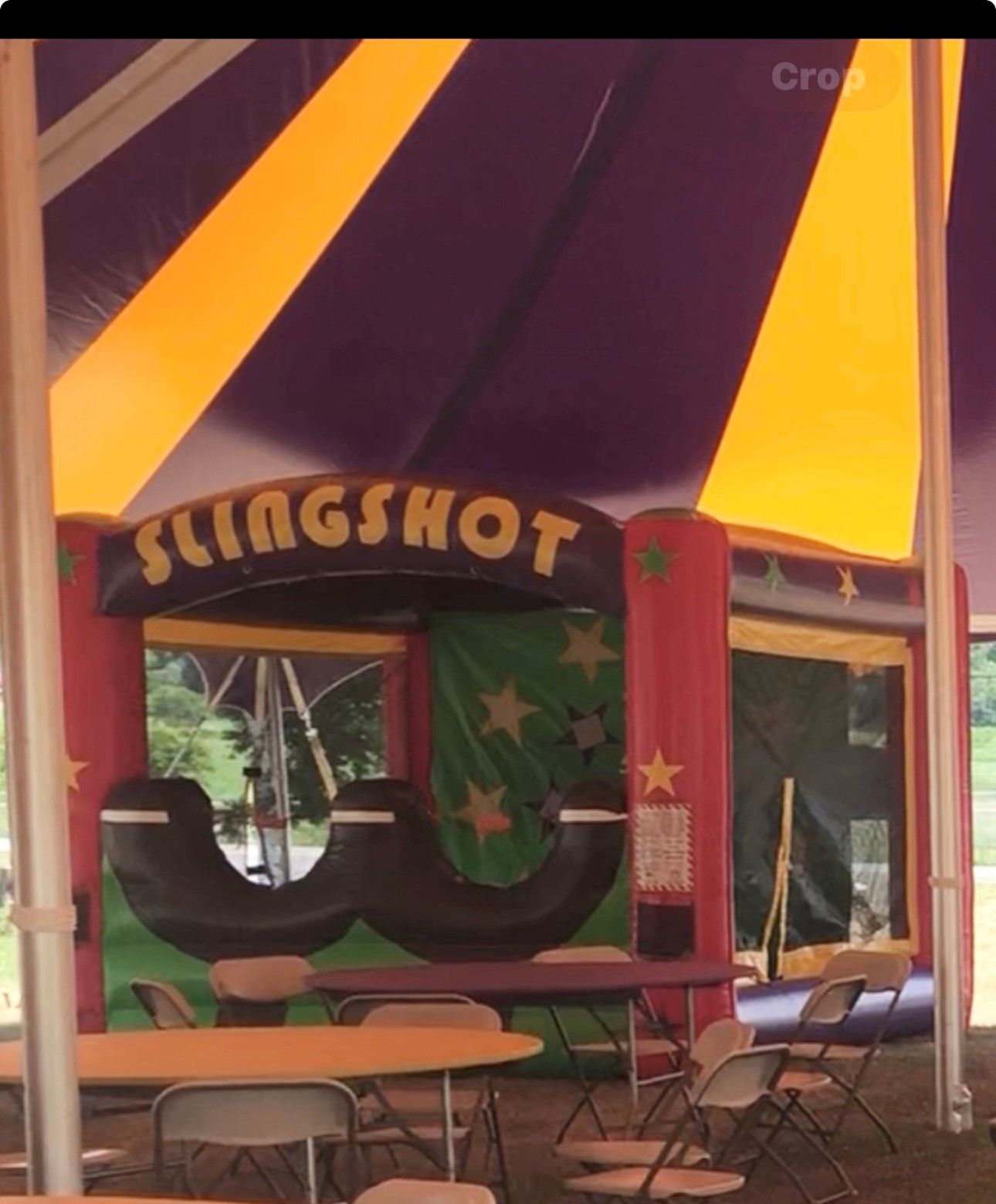 Tables and chairs under a tent that says slingshot