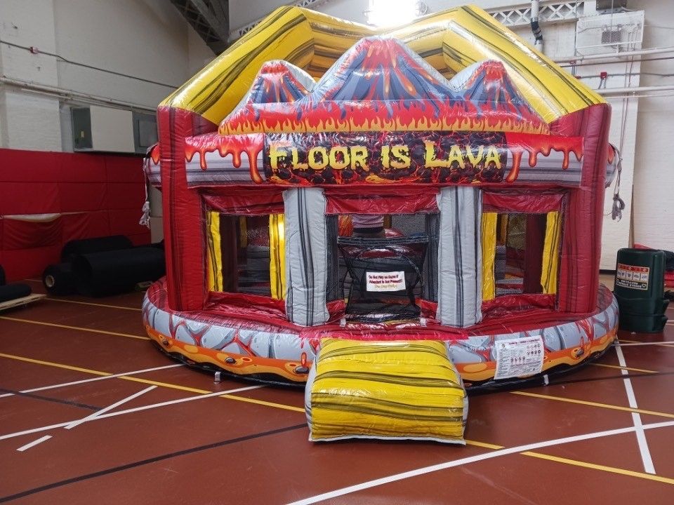 A large inflatable bouncy house is sitting on top of a basketball court.