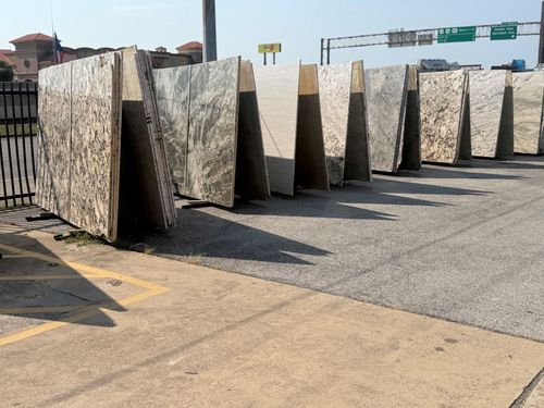 Large stone slabs standing upright in an outdoor yard, with road signs and a building in the background