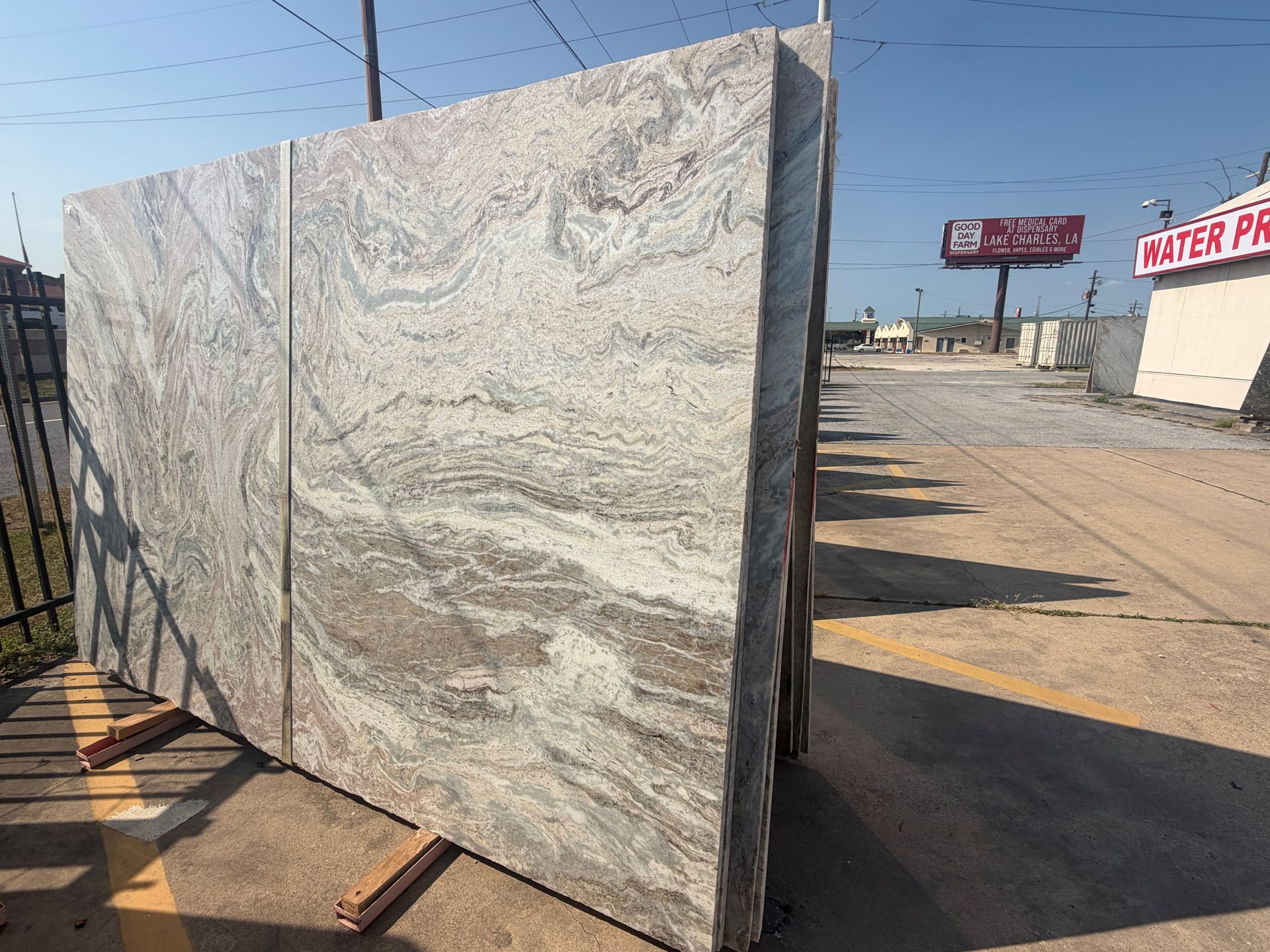 Large polished stone slab leaning outdoors beside a road in bright sunlight.