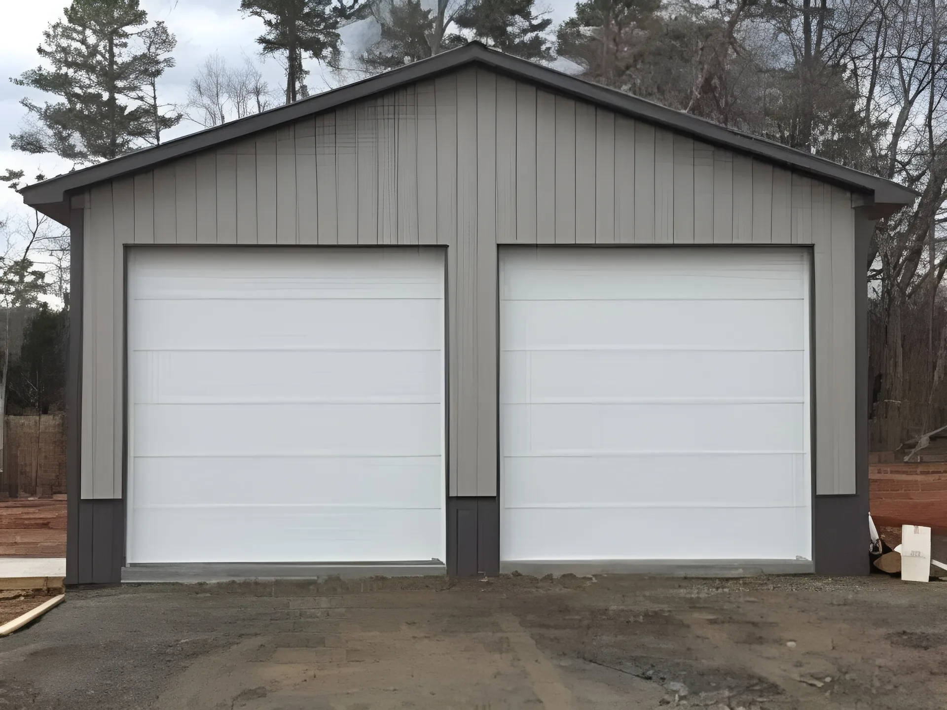 Two-car garage with white doors and gray siding, set on gravel.
