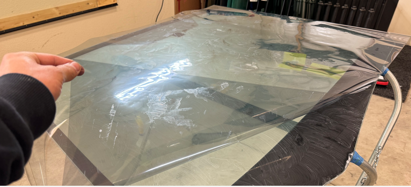 A person is holding a piece of plastic over an aquarium filled with water.