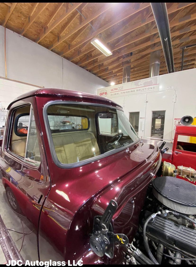 A purple truck is sitting in a garage next to a red truck after