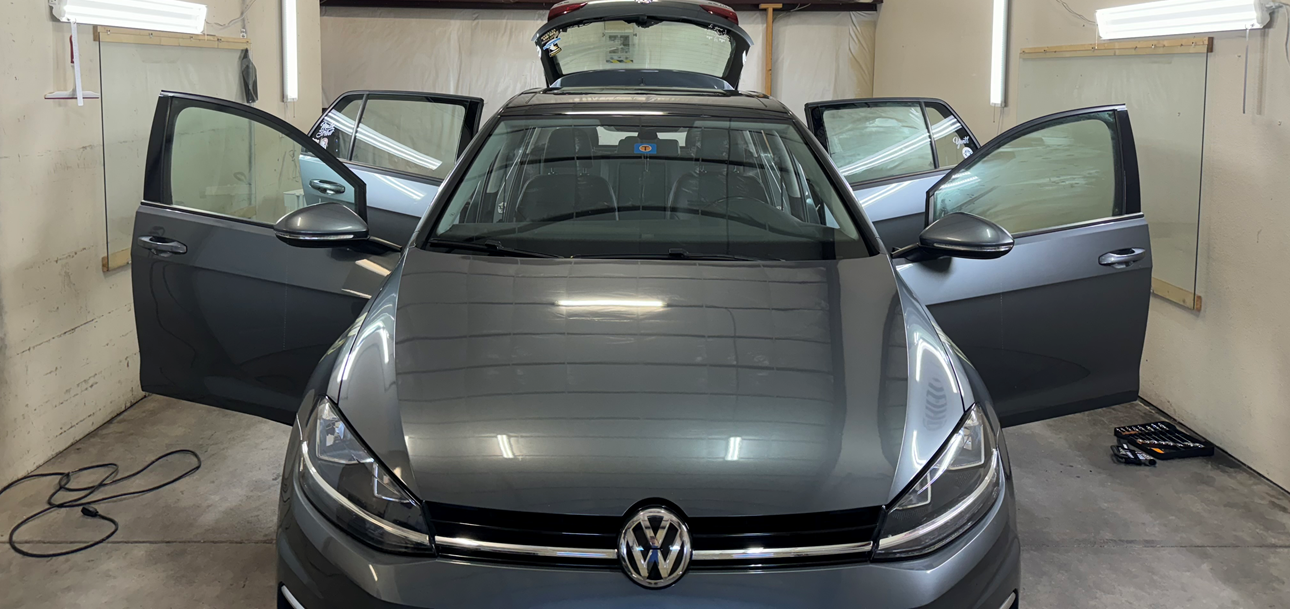 A volkswagen golf is sitting in a garage with its doors open.