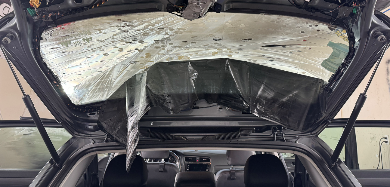 The back of a car with the hood open and a broken windshield.