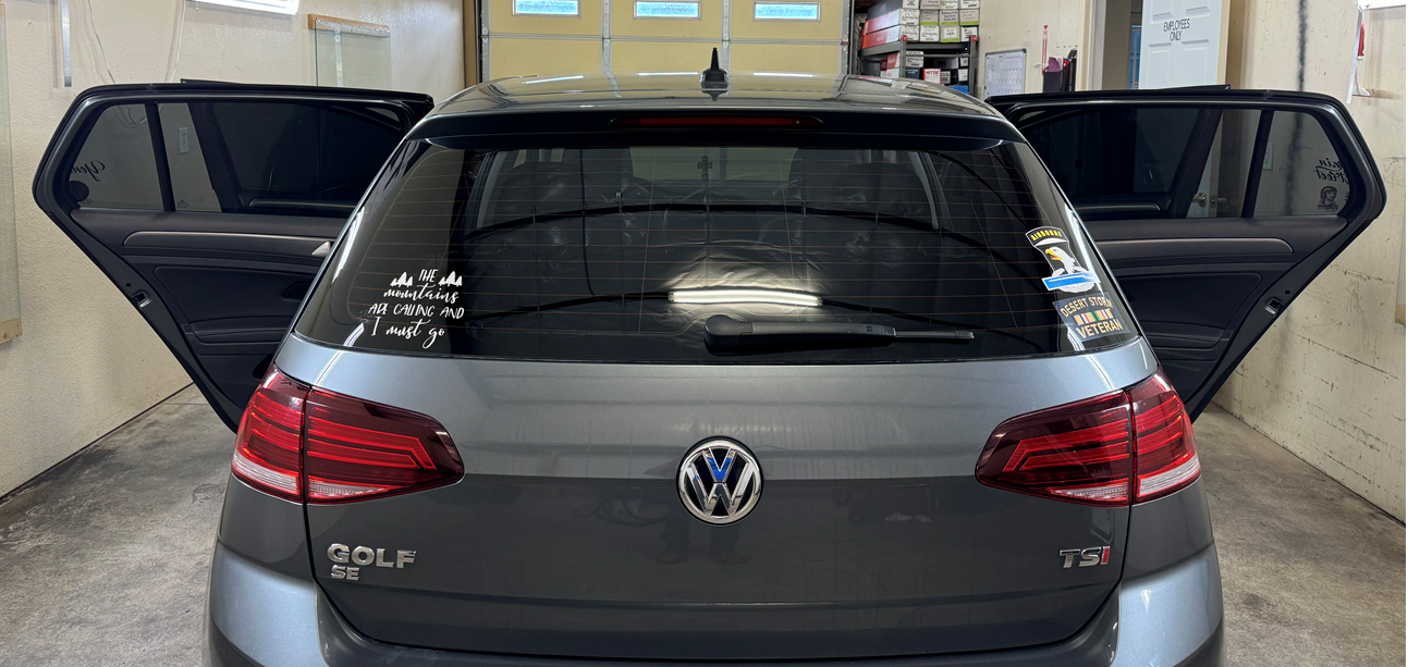 A volkswagen golf is parked in a garage with its doors open.