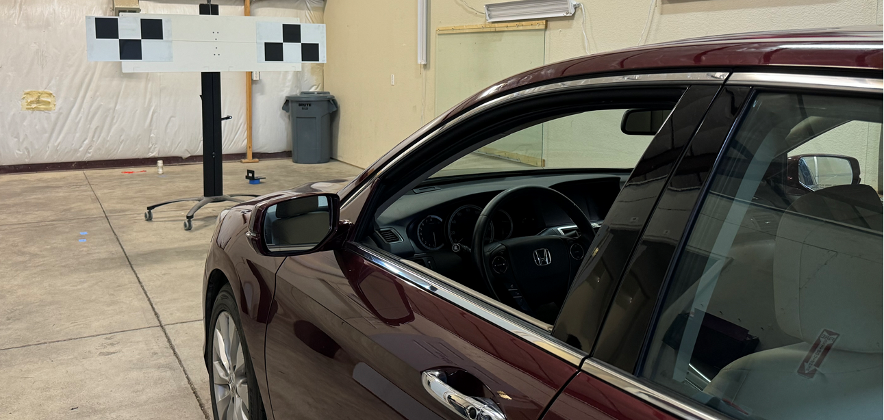 A red car is parked in a garage next to a checkered sign.