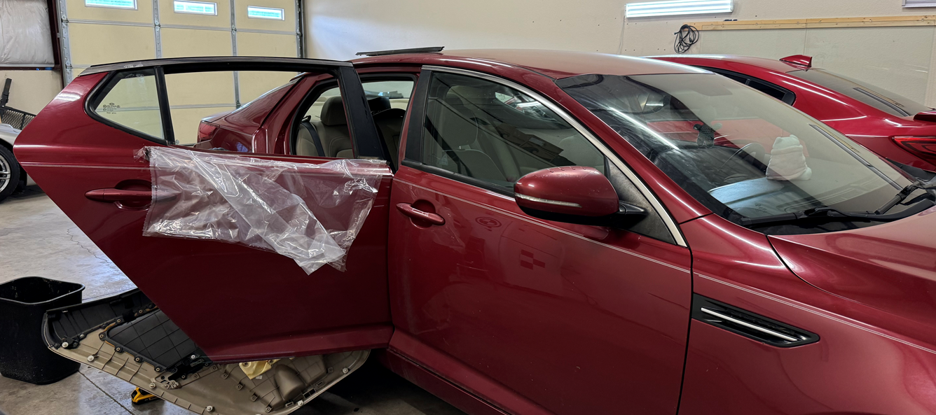 A red car is sitting in a garage with its doors open.