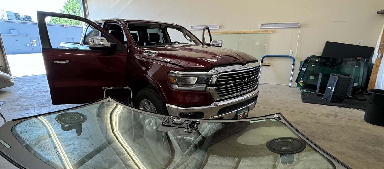 A red ram truck is sitting on top of a glass table in a garage.