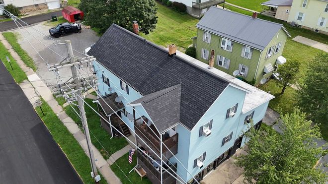 Blue house with dark roof, next to a green house, both in residential area.