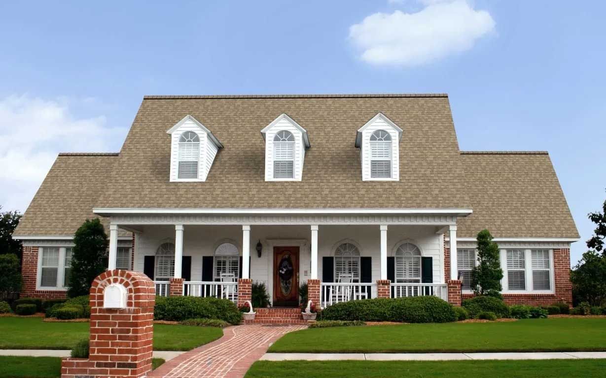 A two-story white house with a brick walkway and lawn on a sunny day.