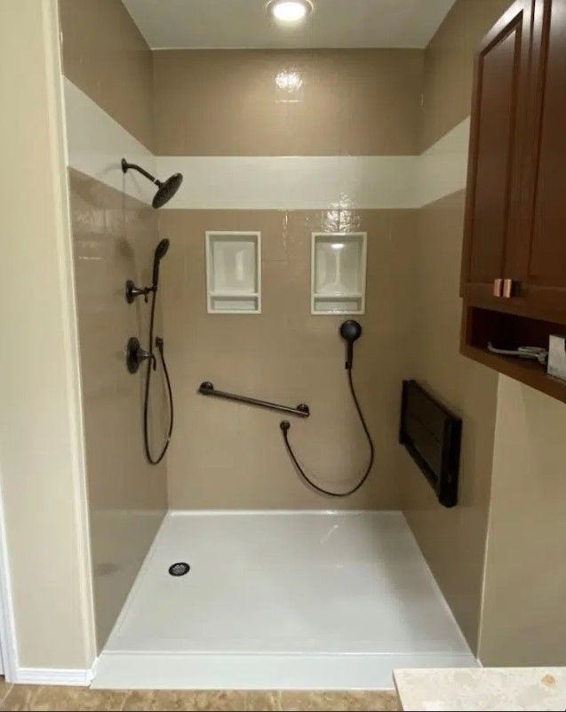 Accessible shower with grab bar, handheld shower, and built-in seating. Neutral tones, overhead light.