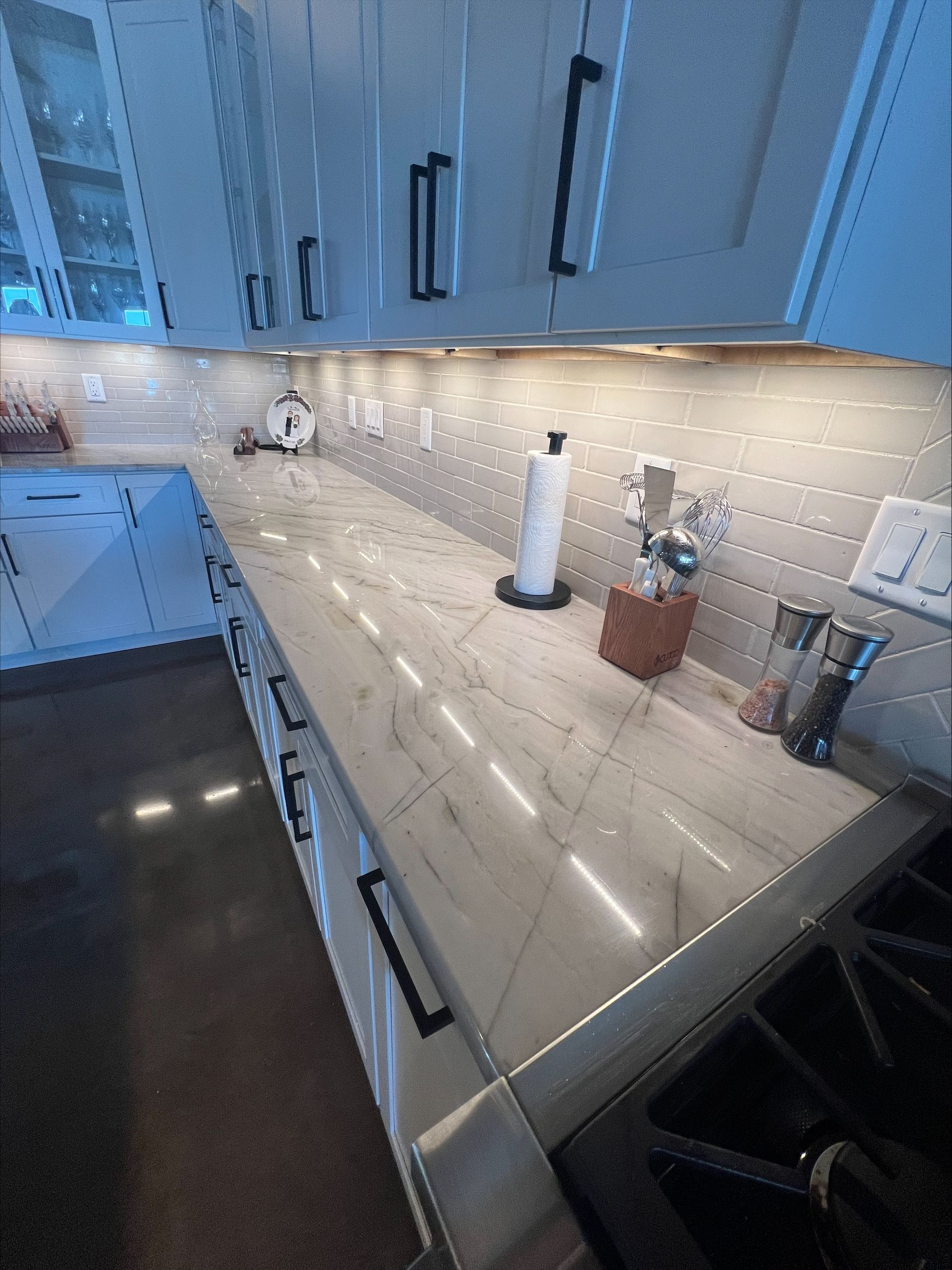 A kitchen with white cabinets and a marble counter top.
