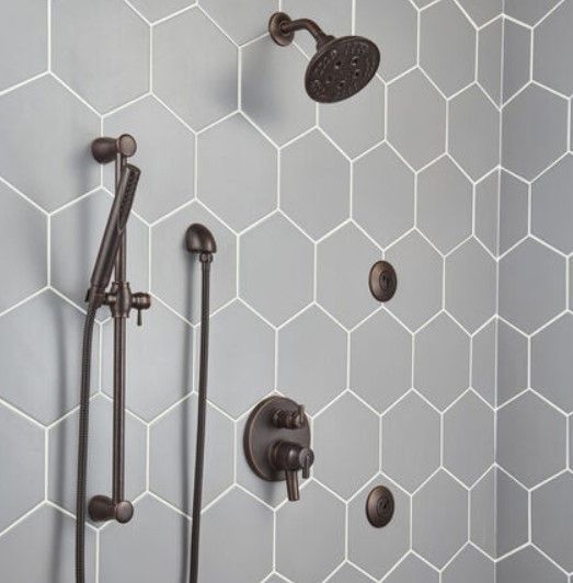A shower with gray tiles and a shower head.