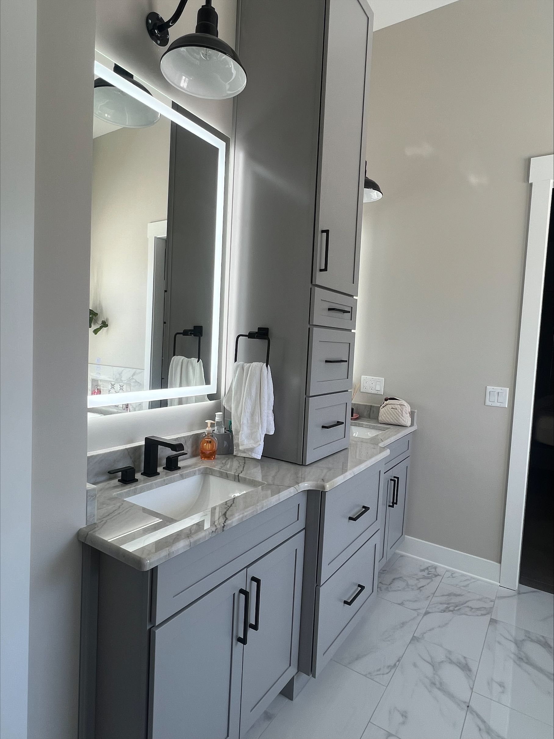 A bathroom with a sink , mirror , cabinets and drawers.