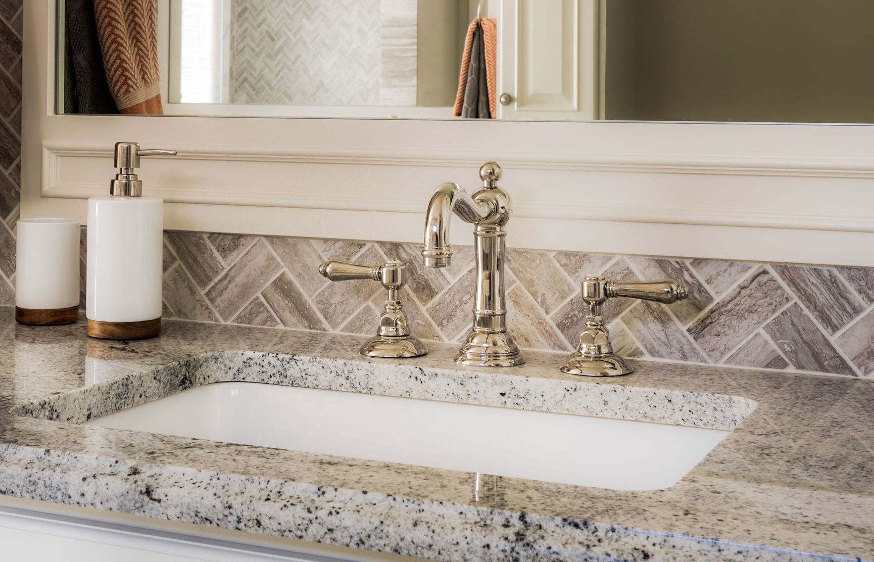 A bathroom sink with a soap dispenser and a mirror.