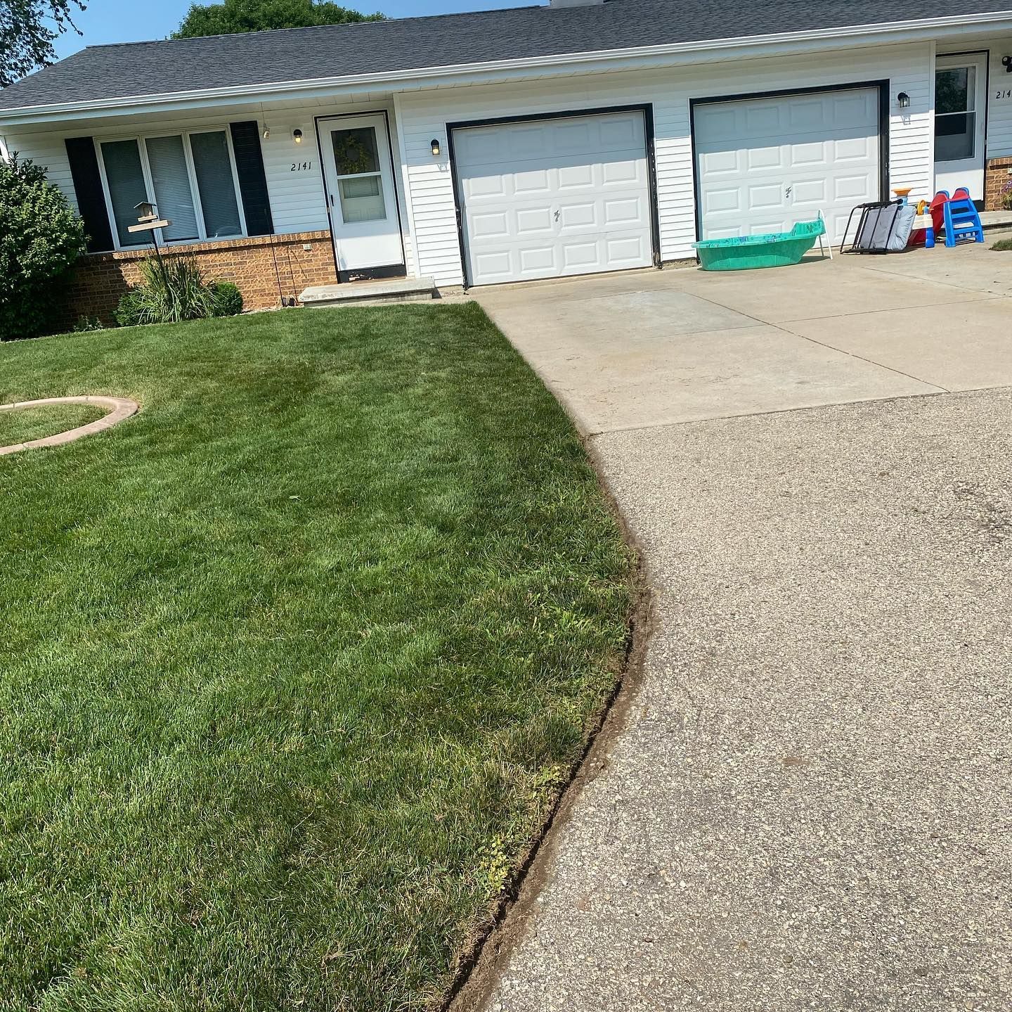 A house with a lush green lawn and a driveway in front of it.