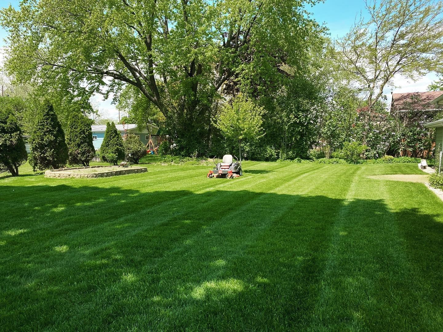 A person is mowing a lush green lawn with a lawn mower.