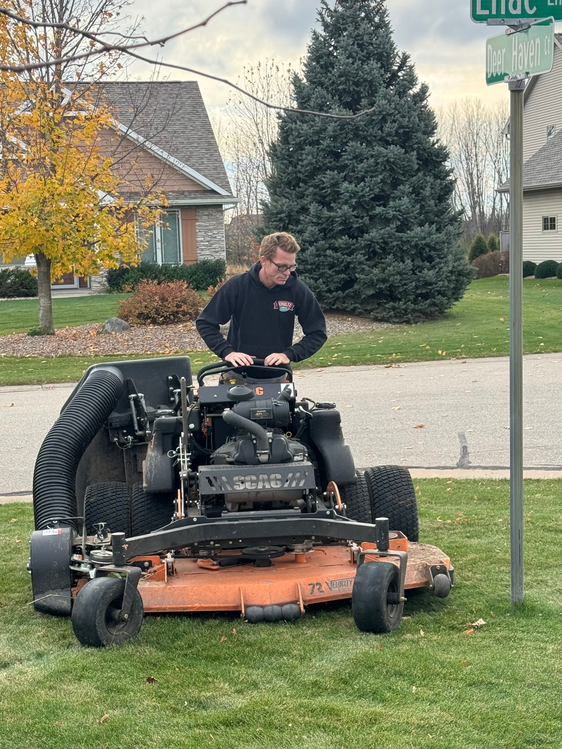 A man is riding a lawn mower on a lush green lawn.