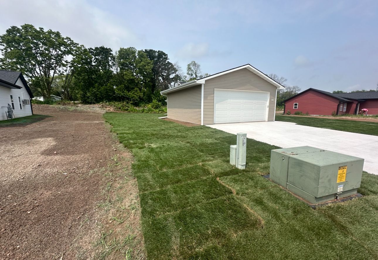 A garage is sitting in the middle of a lush green field.