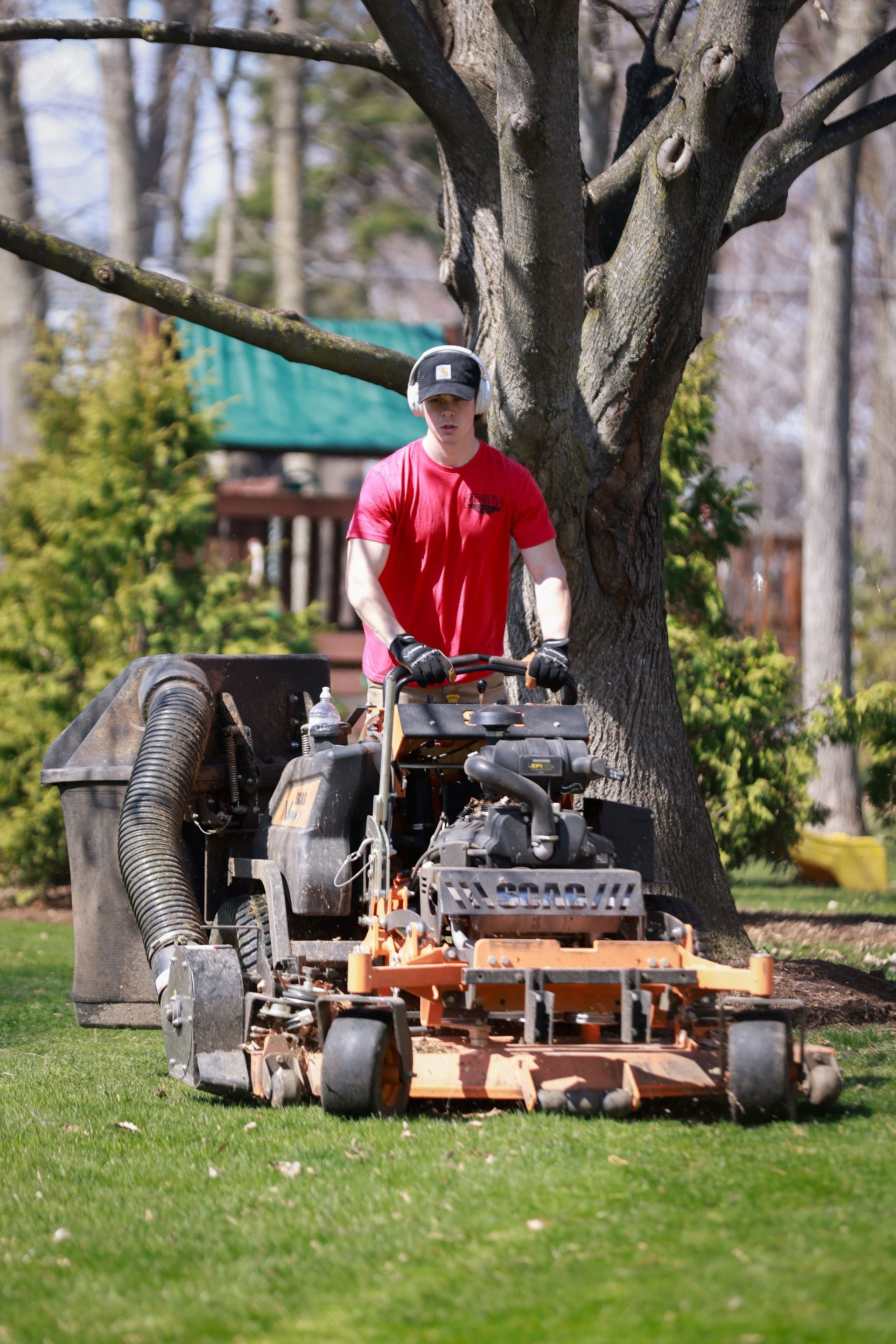 A man is riding a lawn mower on a lush green lawn.