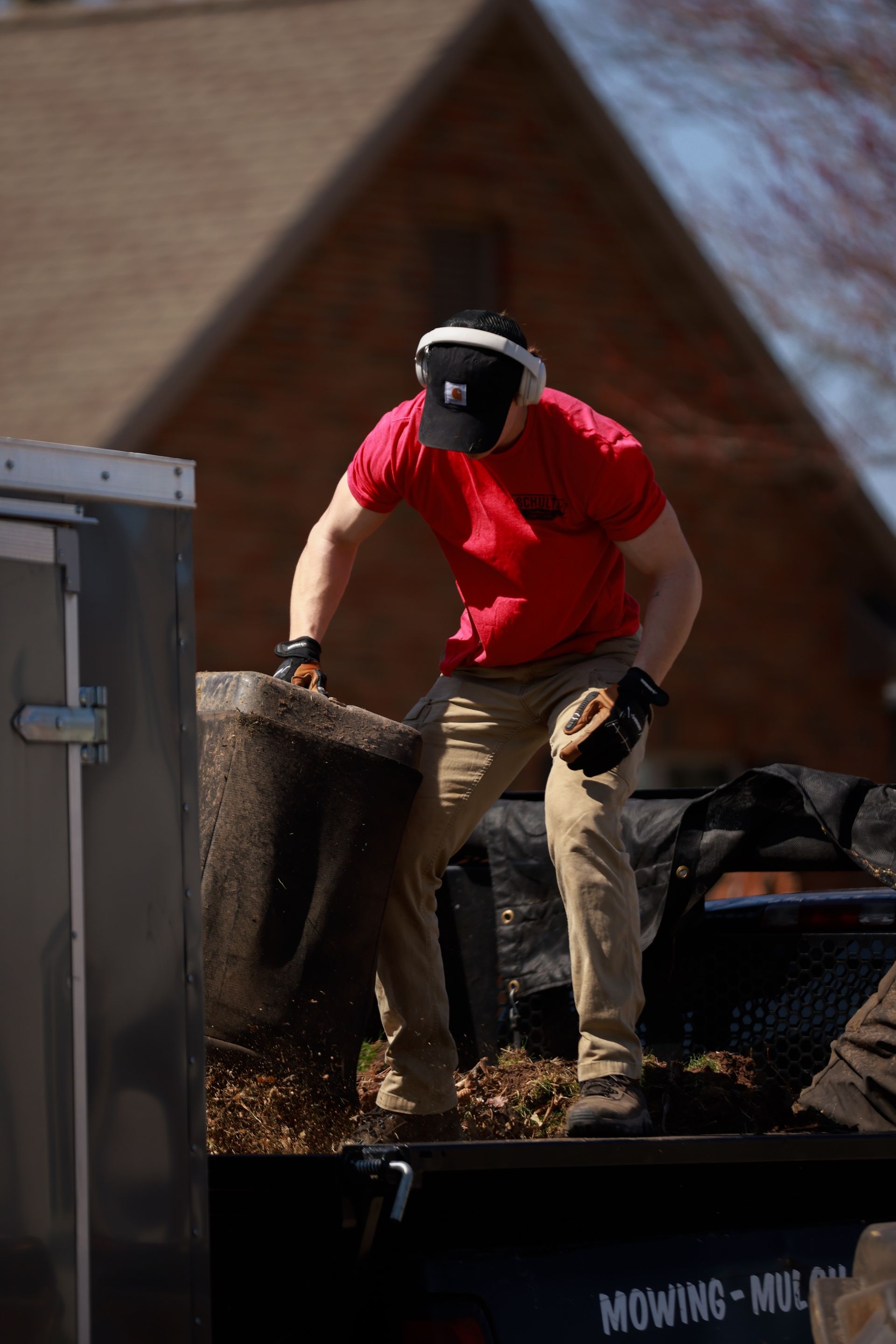 A man in a red shirt is standing on top of a trailer.
