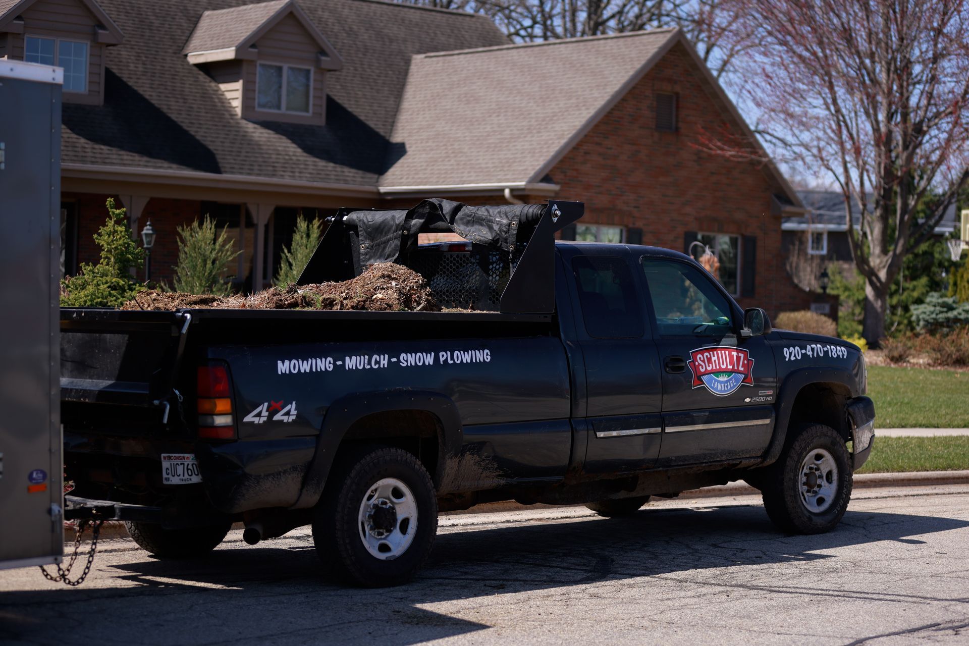 A black truck is parked in front of a brick house