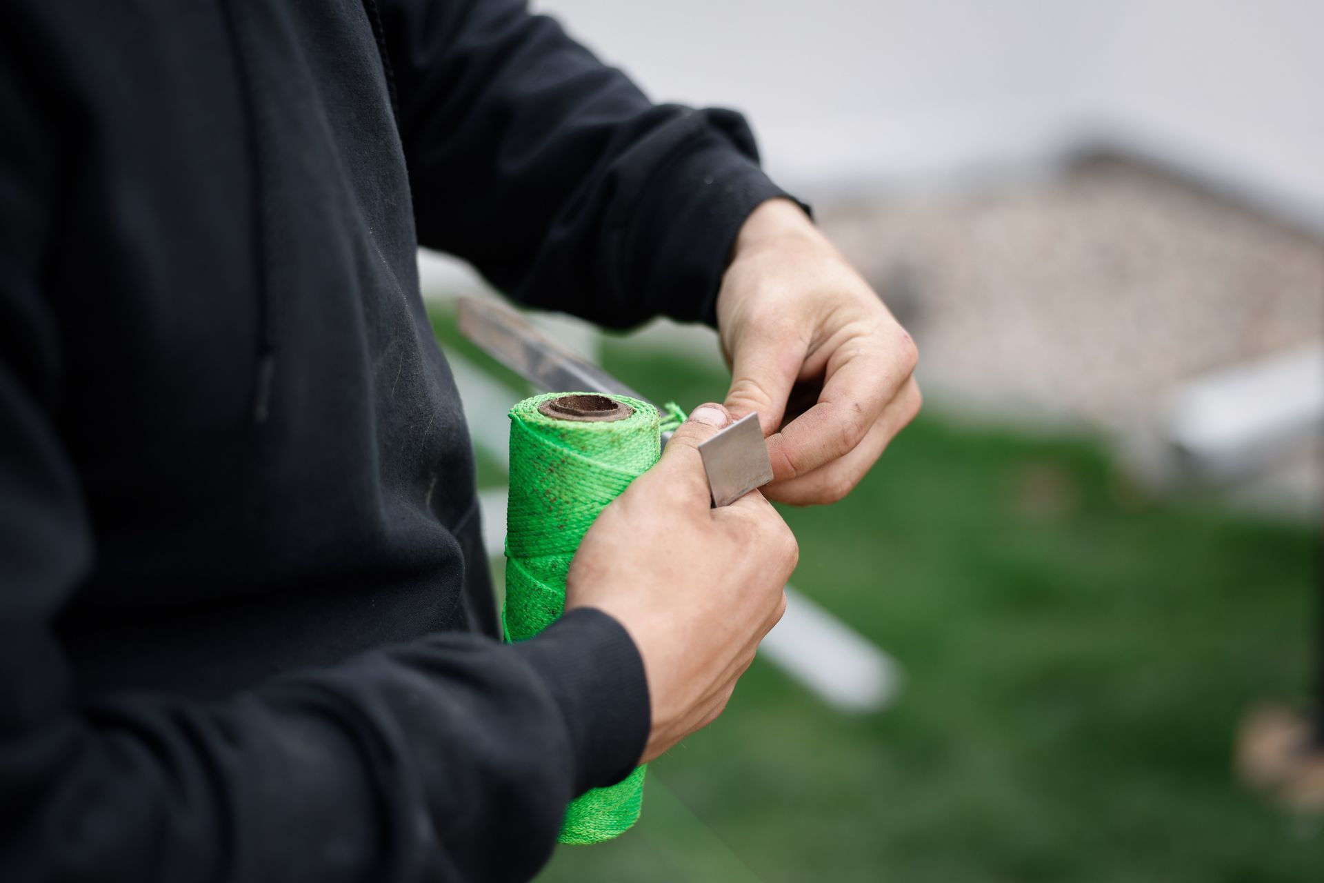 A person is holding a roll of green tape in their hands.