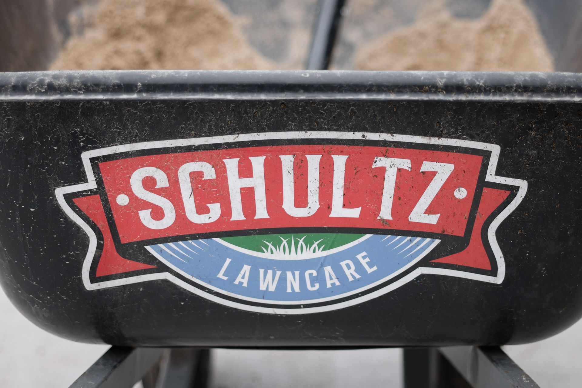 A wheelbarrow with schultz lawncare written on it