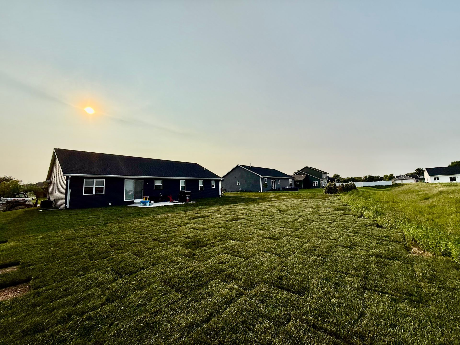 A house is sitting in the middle of a lush green field.
