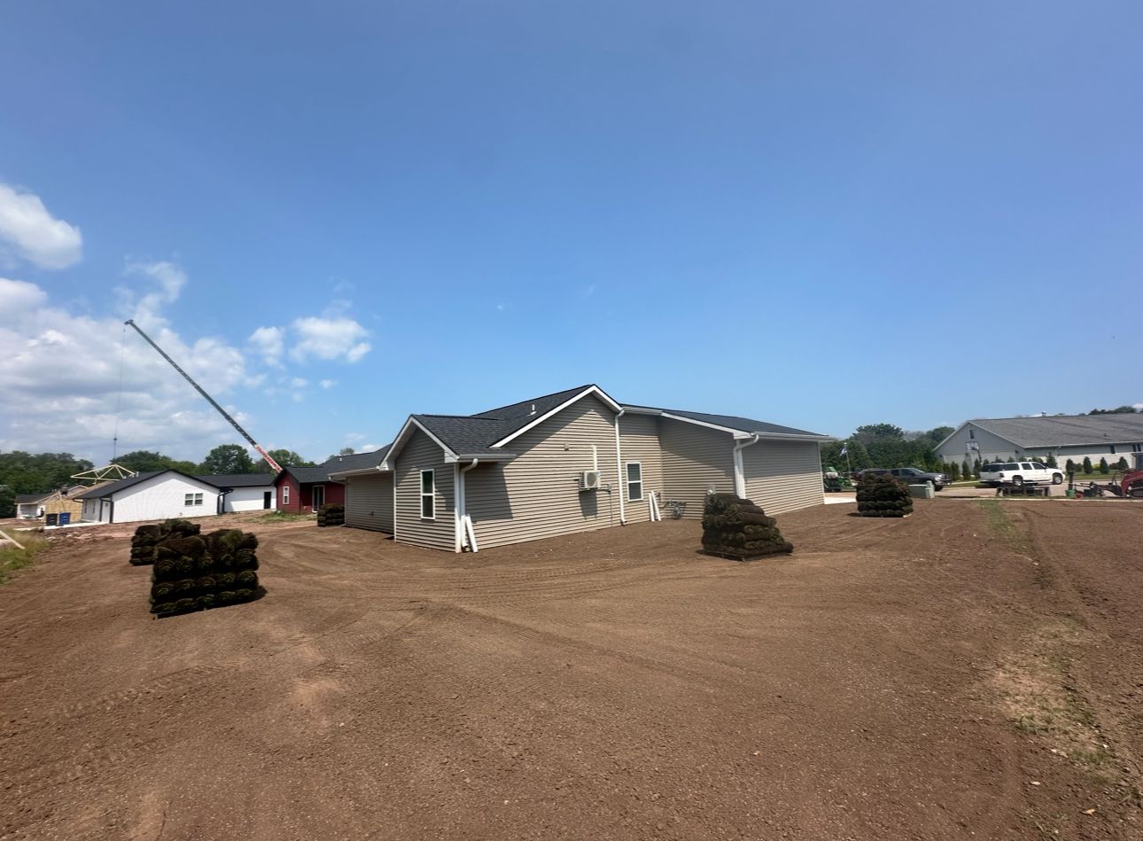 A house is sitting in the middle of a dirt field.