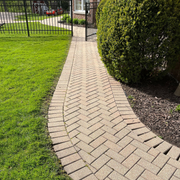 A brick walkway leading to a lush green lawn.