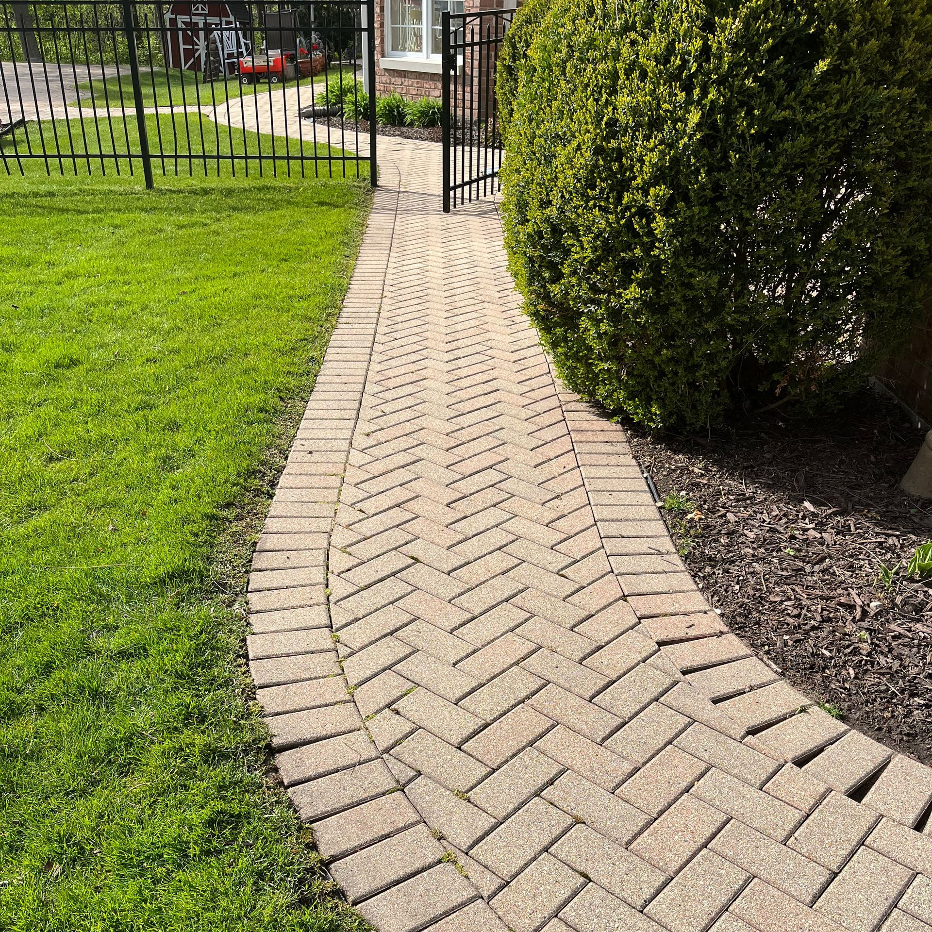 A brick walkway leading to a lush green lawn.