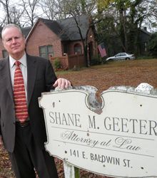 Shane M. Geeter standing by business sign