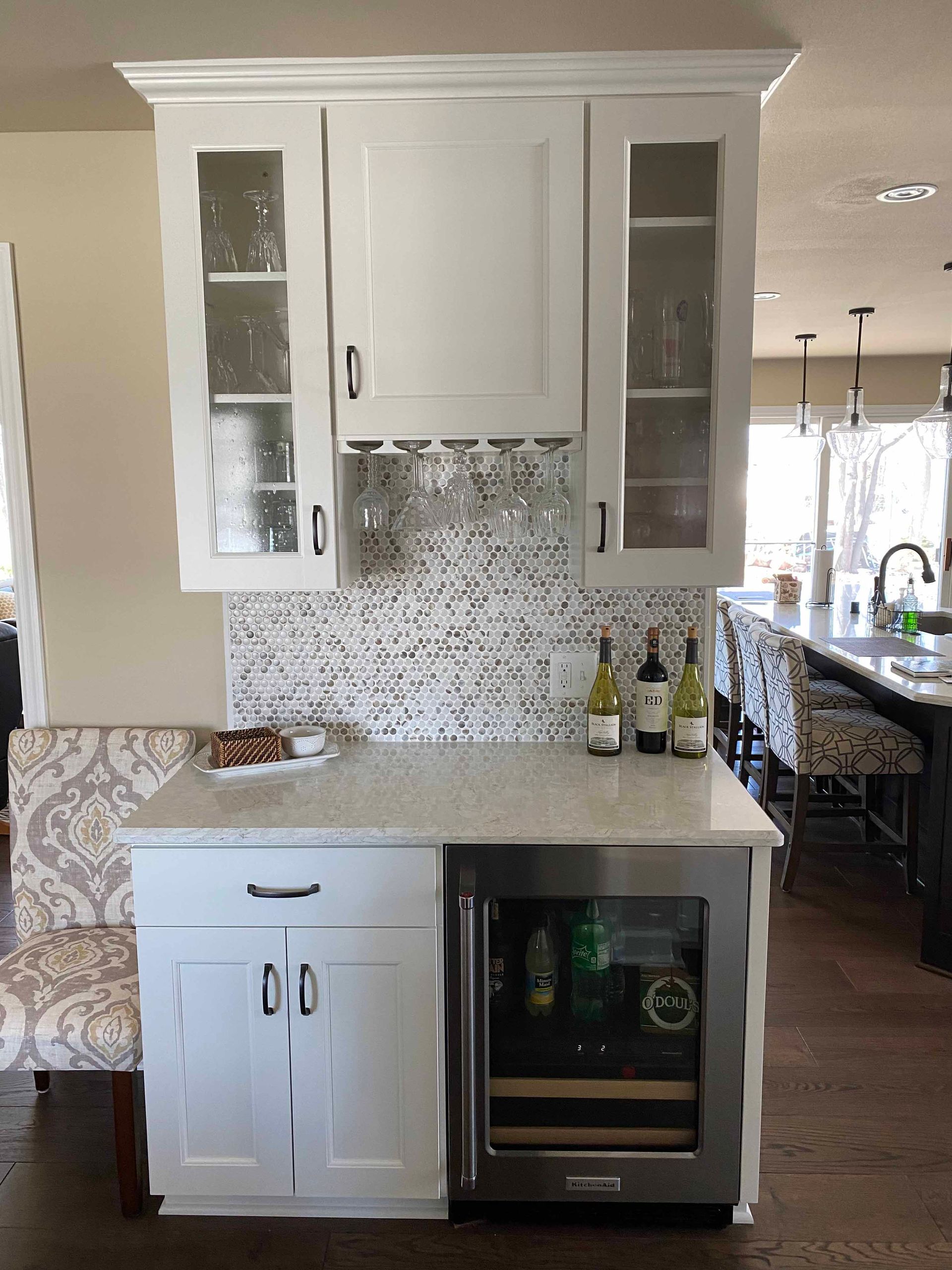 A kitchen with white cabinets and a wine cooler.