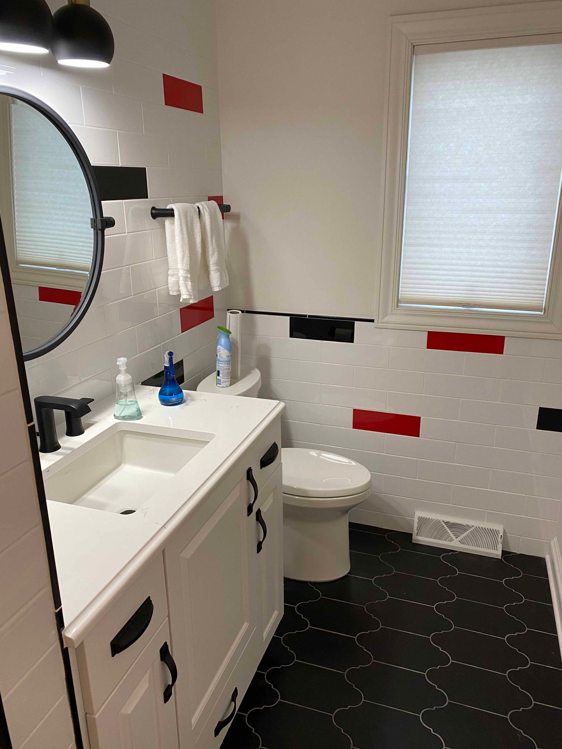 A bathroom with a sink , toilet , mirror and window.