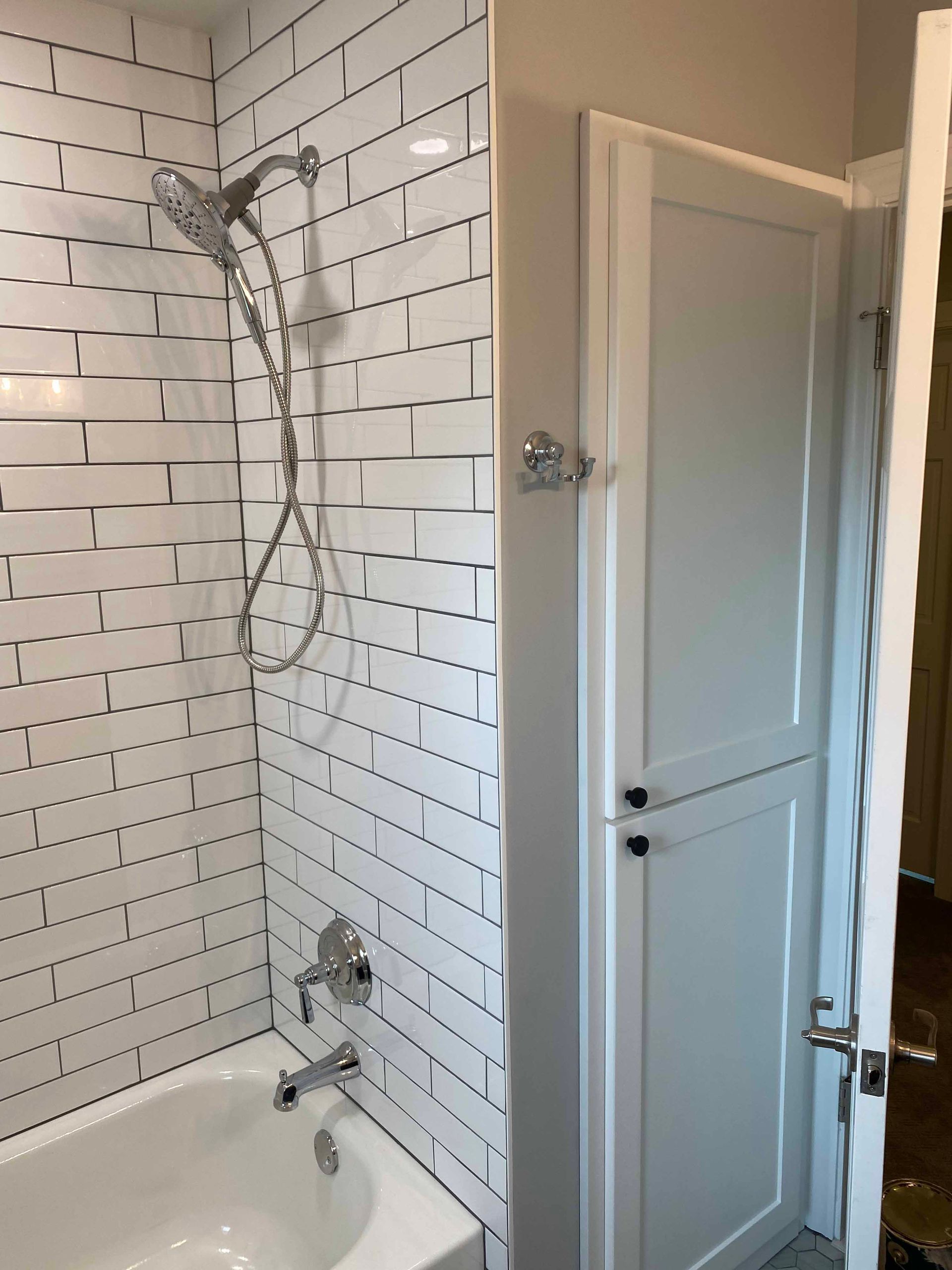 A bathroom with white brick tiles and a bathtub and shower.